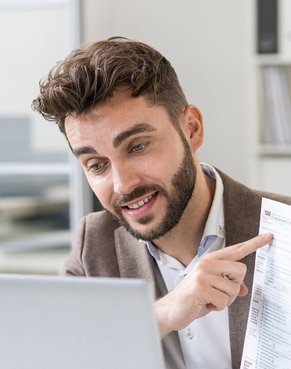 Happy young lawyer pointing at paper while showing it to client on laptop screen